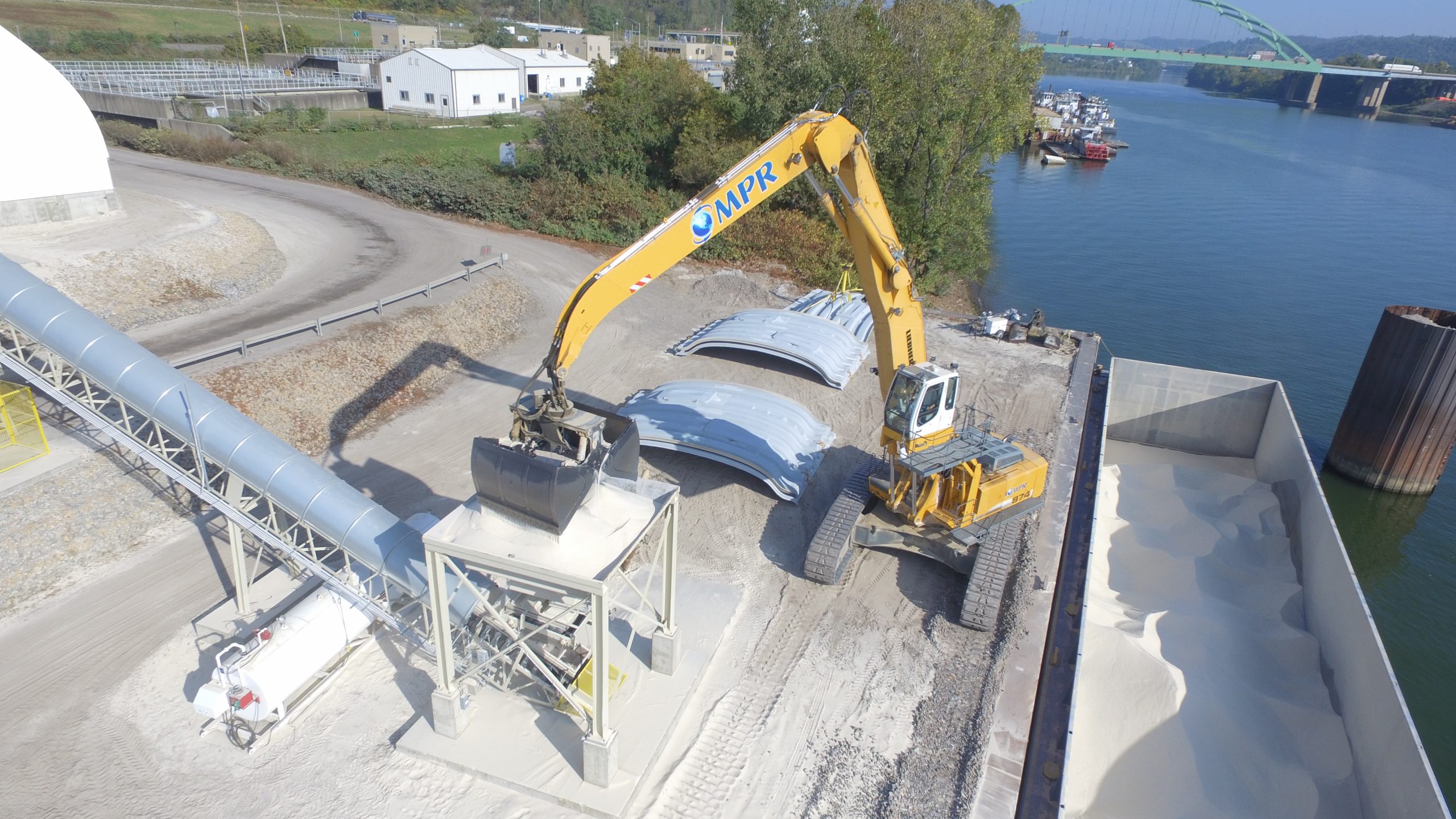 A distant view of a Rotobec attachment releasing a shovel of sand into a funnel.