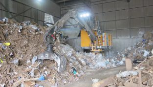Loader with a Rotobec waste grapple in a pile of recyclable material.