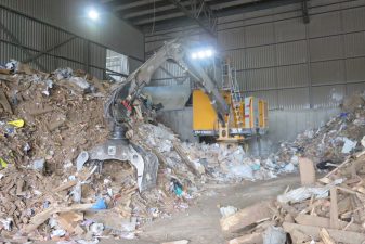 Loader with a Rotobec waste grapple in a pile of recyclable material.