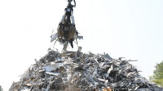 Orange peel grapple in front of a pile of small metal scraps.