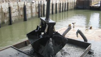 Rotobec clam bucket releasing a shovel of sand on a platform.