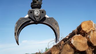 Rotobec log grapple to the left of a pile of logs.