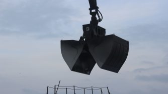 Close view on the opened black Rotobec clam bucket in the air.