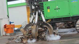 Rotobec orange peel grapples releasing an amount of scrap metal in front of a green loader.