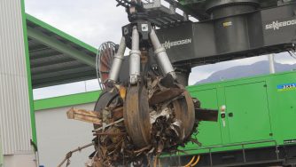 Rotobec orange peel grapples grabbing an amount of scrap metal in front of a green loader.