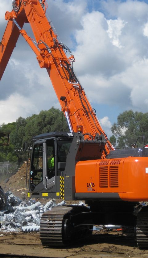 Orange Hitachi loader with a Rotobec orange peel grapple grapping some pieces of metal.