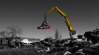 Rotobec loader grabbing a red scrap car with a Rotobec orange peel grapple.