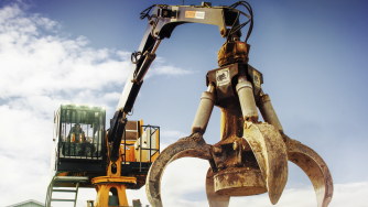 An orange peel grapple on a loader with a man handling it.